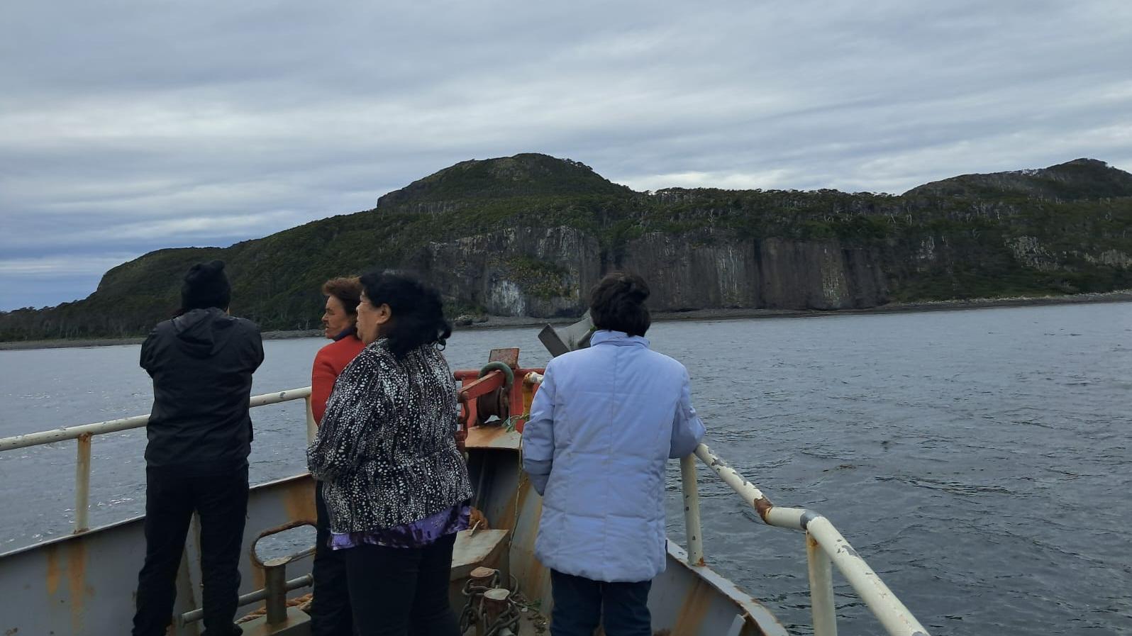 Foto de cuatro mujeres en la proa de una embarcación mirando el horizonte en un día nublado.