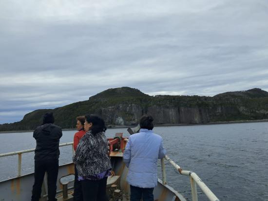Foto de cuatro mujeres en la proa de una embarcación mirando el horizonte en un día nublado.